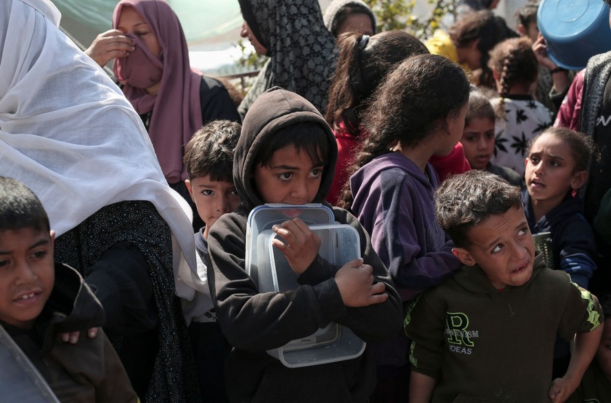 Palestinos deslocados se reúnem para comer em Rafah, no sul da Faixa de Gaza