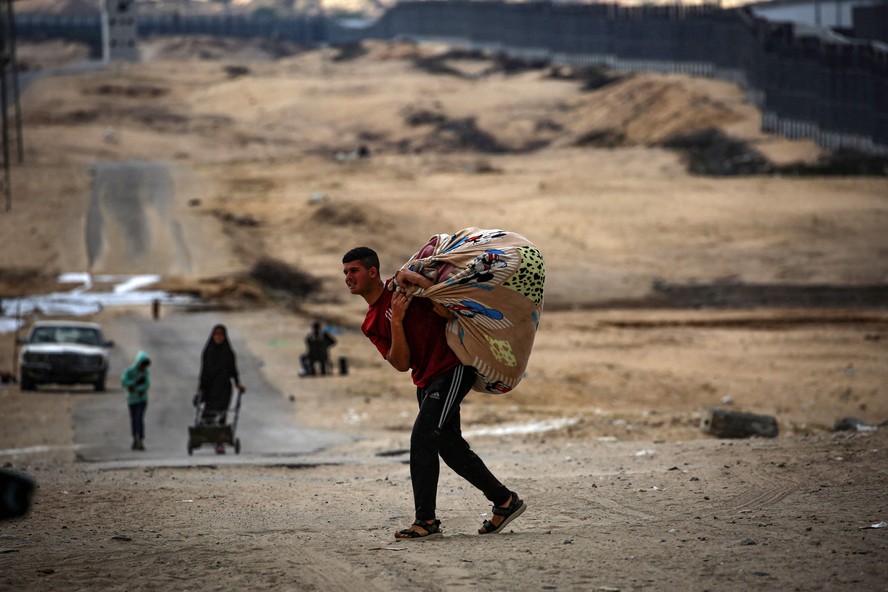 Palestino carrega seus pertences ao deixar Rafah