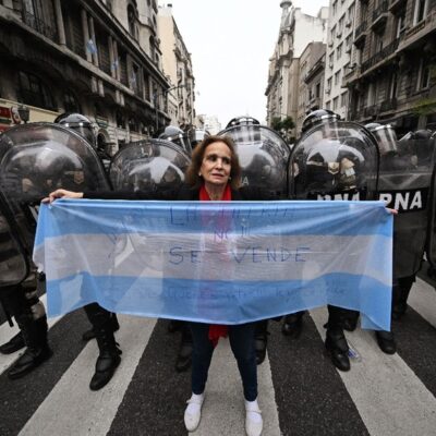 Mulher segura uma bandeira argentina na frente de policiais perto do Congresso Nacional em Buenos Aires, na Argentina