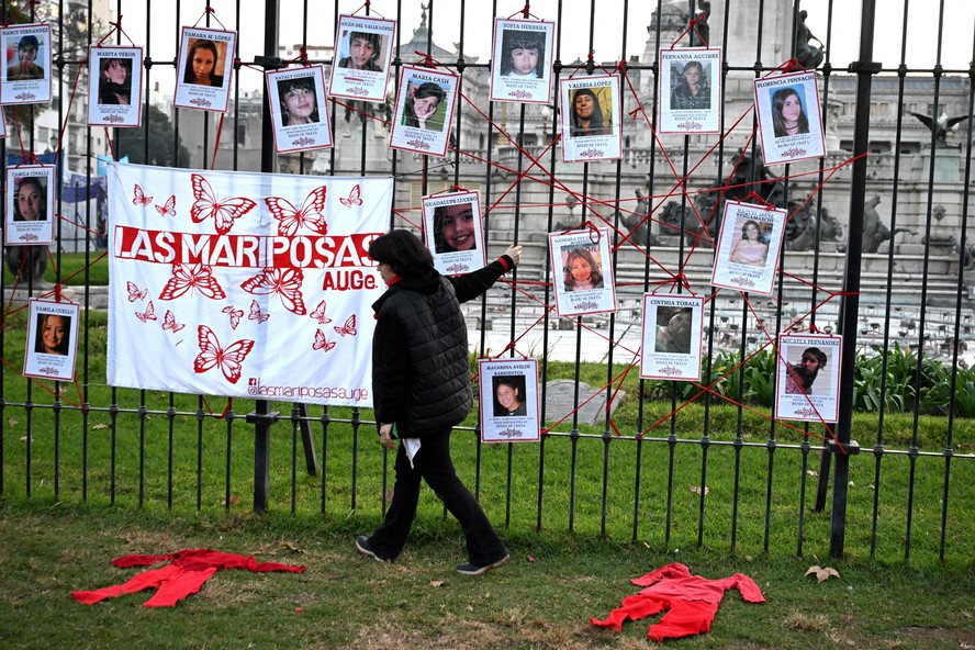 Mulher passa diante de cartazes de mulheres desaparecidas, durante protesto contra a violência de gênero na Argentina