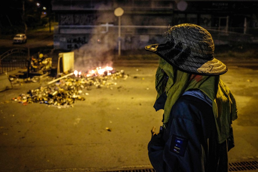 Jovem participa de um bloqueio de estrada com barricadas de fogo no distrito de Auteuil, em Nova Caledônia