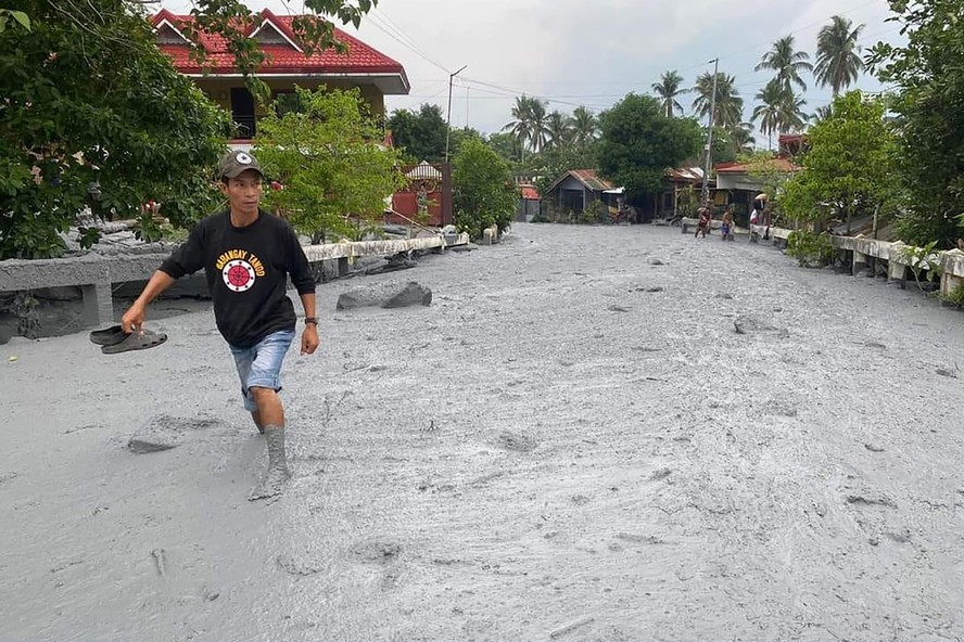 Residente atravessa lahar da erupção do vulcão Monte Kanlaon ao longo de uma estrada na vila de Biaknabato no município de La Castellana.