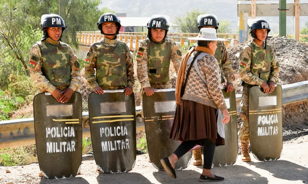 Military personnel stand in formation as they are deployed, while a woman walks past in front of them, after Bolivian President Rodrigo Paz declared a nationwide state of emergency following weeks of violence and blockades,  in Cochabamba, Bolivia, June 20, 2026. REUTERS/Patricia PintoTPX IMAGES OF THE DAY