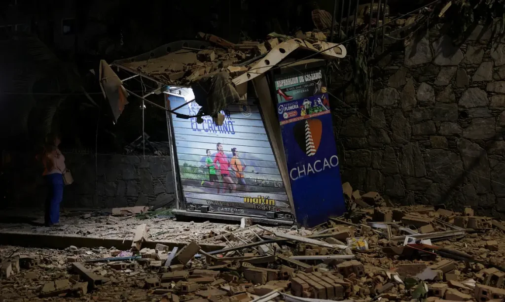 A person looks on near rubble at the site of a collapsed building, after an earthquake, in Caracas, Venezuela, June 24, 2026. REUTERS/Gaby Oraa