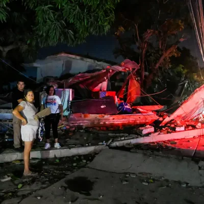 People stand next to a destroyed building after earthquakes, in La Guaira, Venezuela, June 25, 2026. REUTERS/Maxwell Briceno