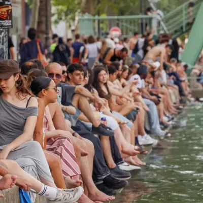 People sit along the Canal Saint-Martin to find some relief from the heat as public swimming having been allowed earlier on part of it due to rising of temperatures, in Paris as a heatwave hits a large of France, June 18, 2026. REUTERS/Alice Sacco