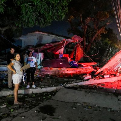 People stand next to a destroyed building after earthquakes, in La Guaira, Venezuela, June 25, 2026. REUTERS/Maxwell Briceno