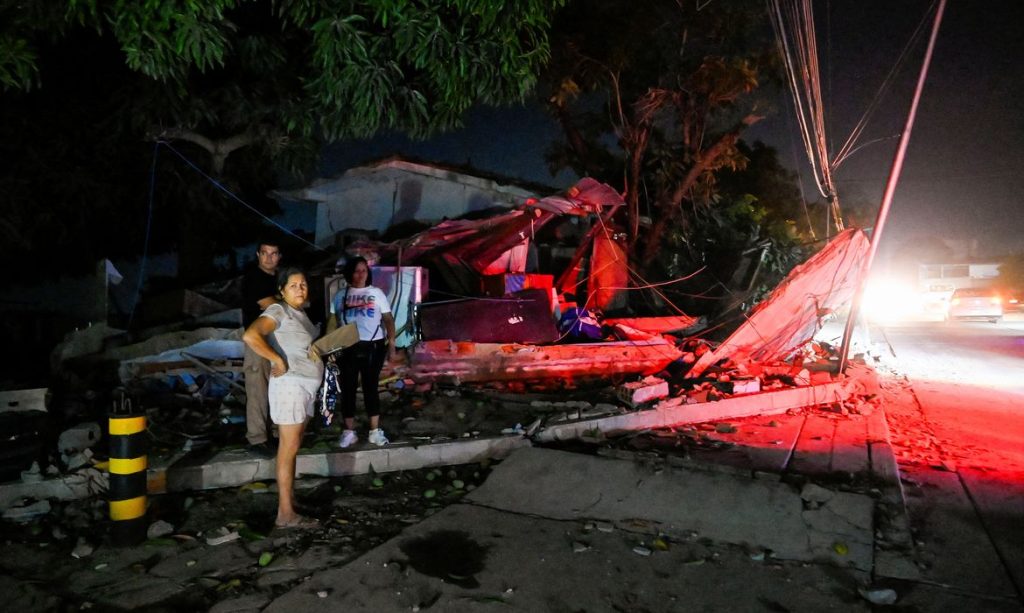 People stand next to a destroyed building after earthquakes, in La Guaira, Venezuela, June 25, 2026. REUTERS/Maxwell Briceno