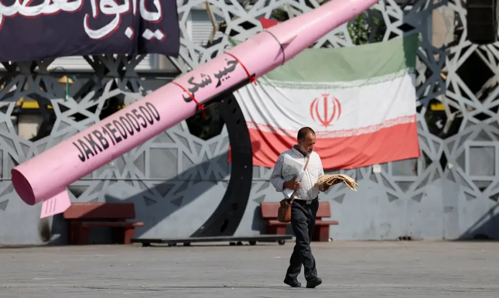 A man walks next to a symbolic mockup of an Iranian missile and an Iranian flag at Imam Hussein Square in Tehran, Iran, July 12, 2026. Foto: Majid Asgaripour/WANA/REUTERS/Proibida reprodução