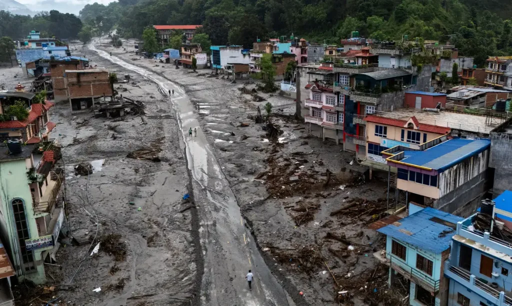 Imagem captada por um drone mostra pessoas caminhando por uma estrada e casas cobertas de lama após enchentes e deslizamentos de terra fatais, em Devighat, distrito de Nuwakot, no Nepal
30 de agosto de 2026
REUTERS/Athit Perawongmetha