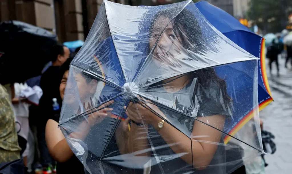 Uma pessoa segura um guarda-chuva para se proteger dos ventos fortes antes da chegada do tufão Dolphin em Xangai, na China, em 9 de agosto de 2026. REUTERS/Go Nakamura