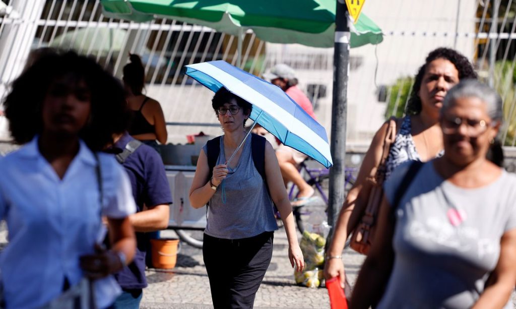 Rio de Janeiro (RJ), 17/02/2024 -Transeuntes se protegem do forte calor nas ruas do centro da cidade. Cidade do Rio de Janeiro atinge nível 4 de calor. Marco é caracterizado por temperaturas que podem chegar a 44ºC  Foto: Tânia Rêgo/Agência Brasil