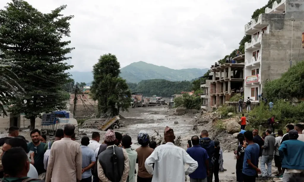 People stand near mud covered houses and a road, following a flash flood at Trishuli in Nuwakot district, Nepal, August 26, 2026. REUTERS/Navesh Chitrakar