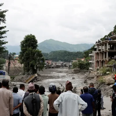 People stand near mud covered houses and a road, following a flash flood at Trishuli in Nuwakot district, Nepal, August 26, 2026. REUTERS/Navesh Chitrakar