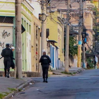 Two armed police officers walk through an almost deserted street in Rio De Janeiro. At least eleven people have died in a police operation against the heads of the Comando Vermelho (Red Command) Criminal organization. (Best possible quality)