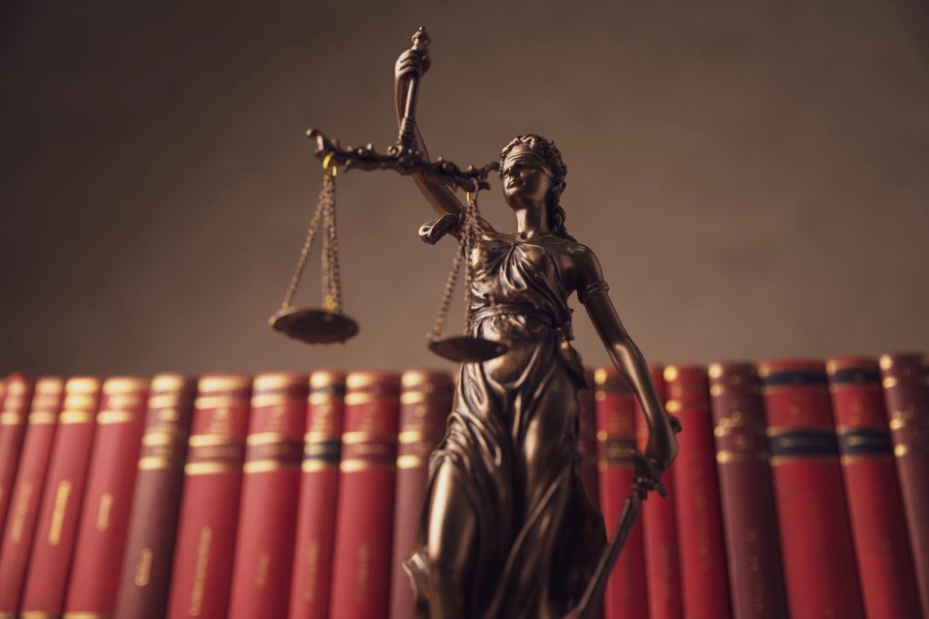 imagem da estatua simbolo da justiça, em frente a livros
