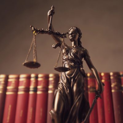 imagem da estatua simbolo da justiça, em frente a livros