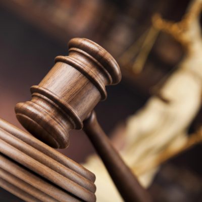 martelo da justiça em plano incial com estatua da justiça ao fundo