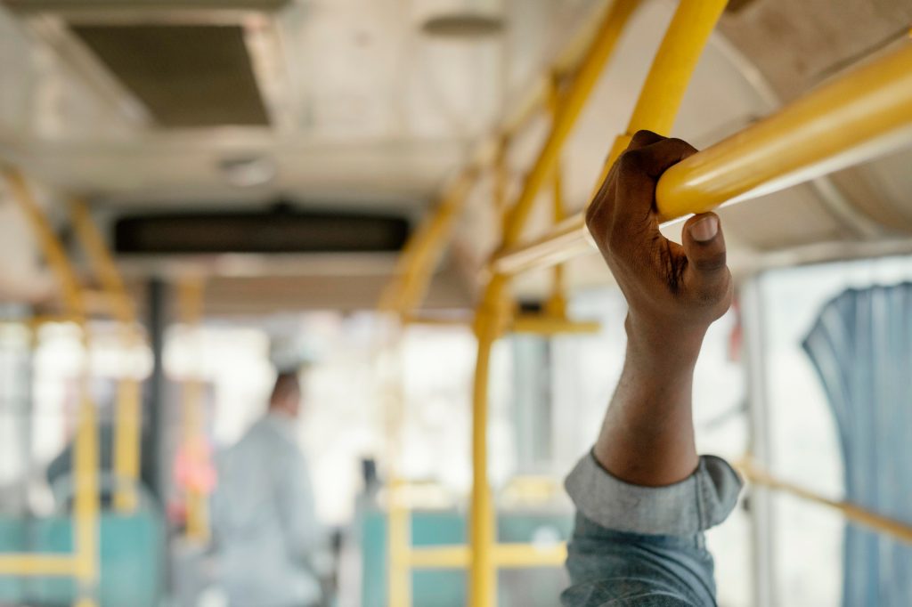 mão de pessoa segurando apoio em transporte publico