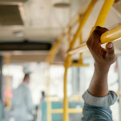 mão de pessoa segurando apoio em transporte publico